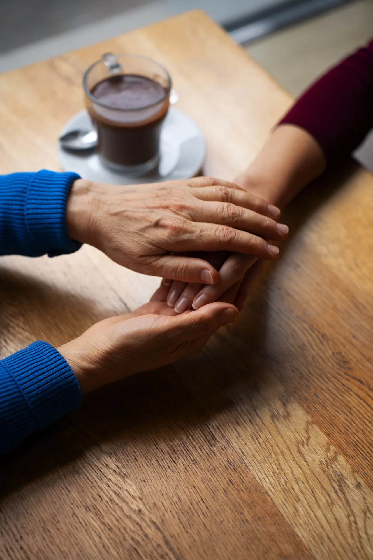 Sonaly et les notaires : deux paires de mains entrelacées sur une table en bois, symbolisant la confiance, l’accompagnement et la gestion des formalités CESU après décès.